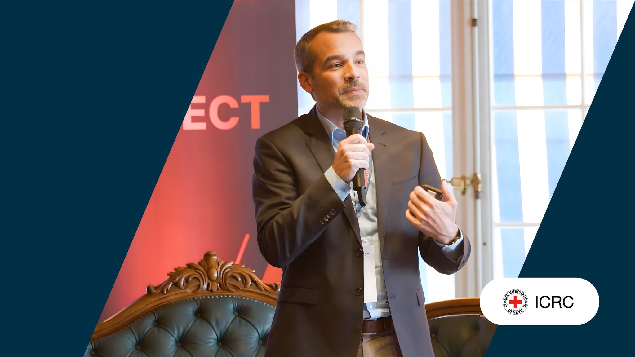 Speaker from ICRC presenting on stage with ICRC logo on the lower right