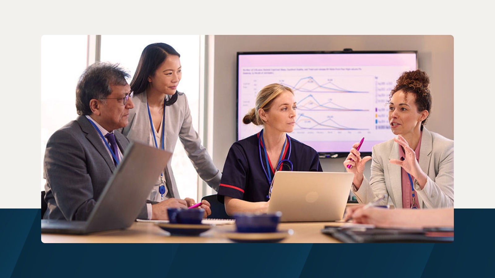 A group of professionals, including a healthcare worker and a business consultant, engaged in a discussion with a laptop and data charts in the background, representing intelligent forecasting and data-driven planning.