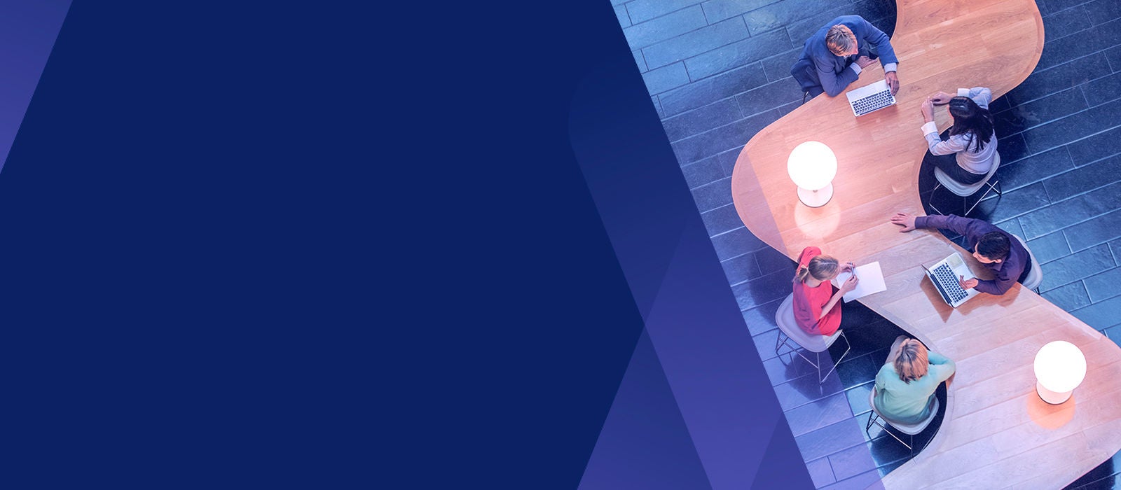 A team sittingin long wood table for a meeting. 