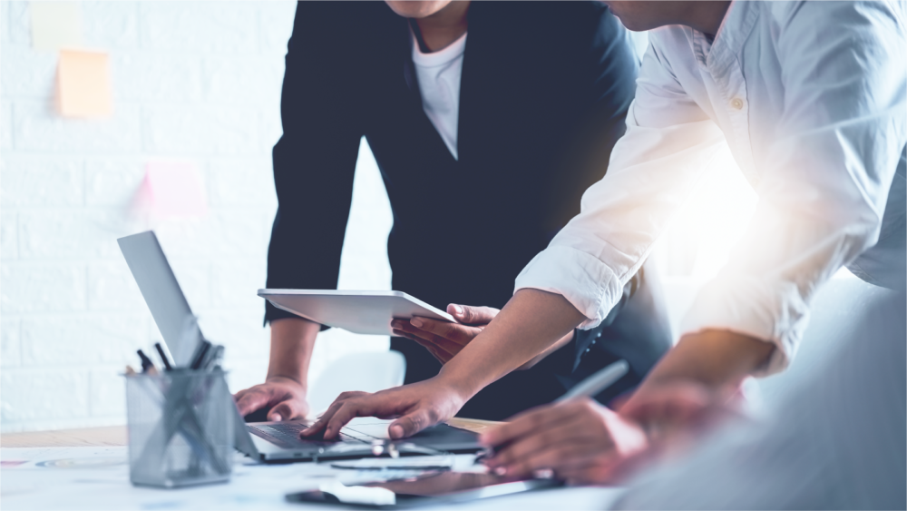 Three coworkers collaborating over an office meeting room table