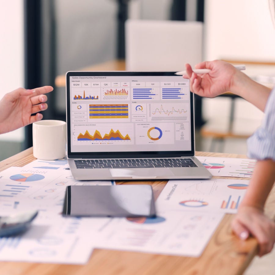laptop on a table with scattered papers, collaborating on a project.