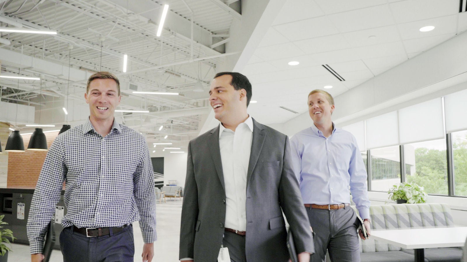three men walking through unum office smiling