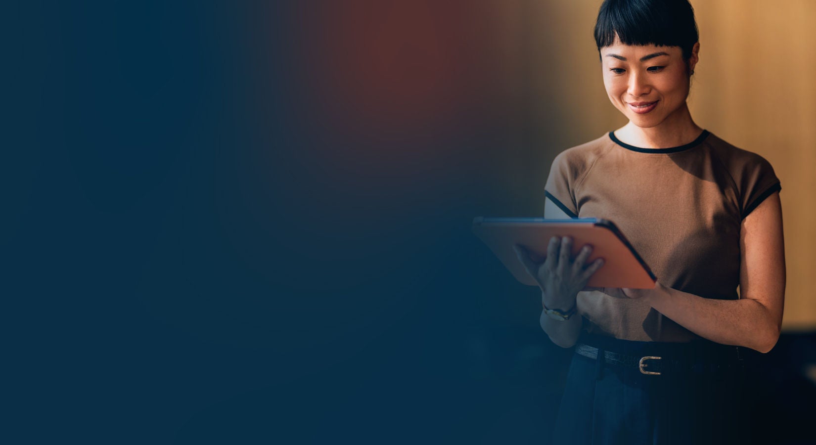 Woman smiling while using a tablet in a warmly lit indoor space, with a dark blue gradient overlay on the left side.