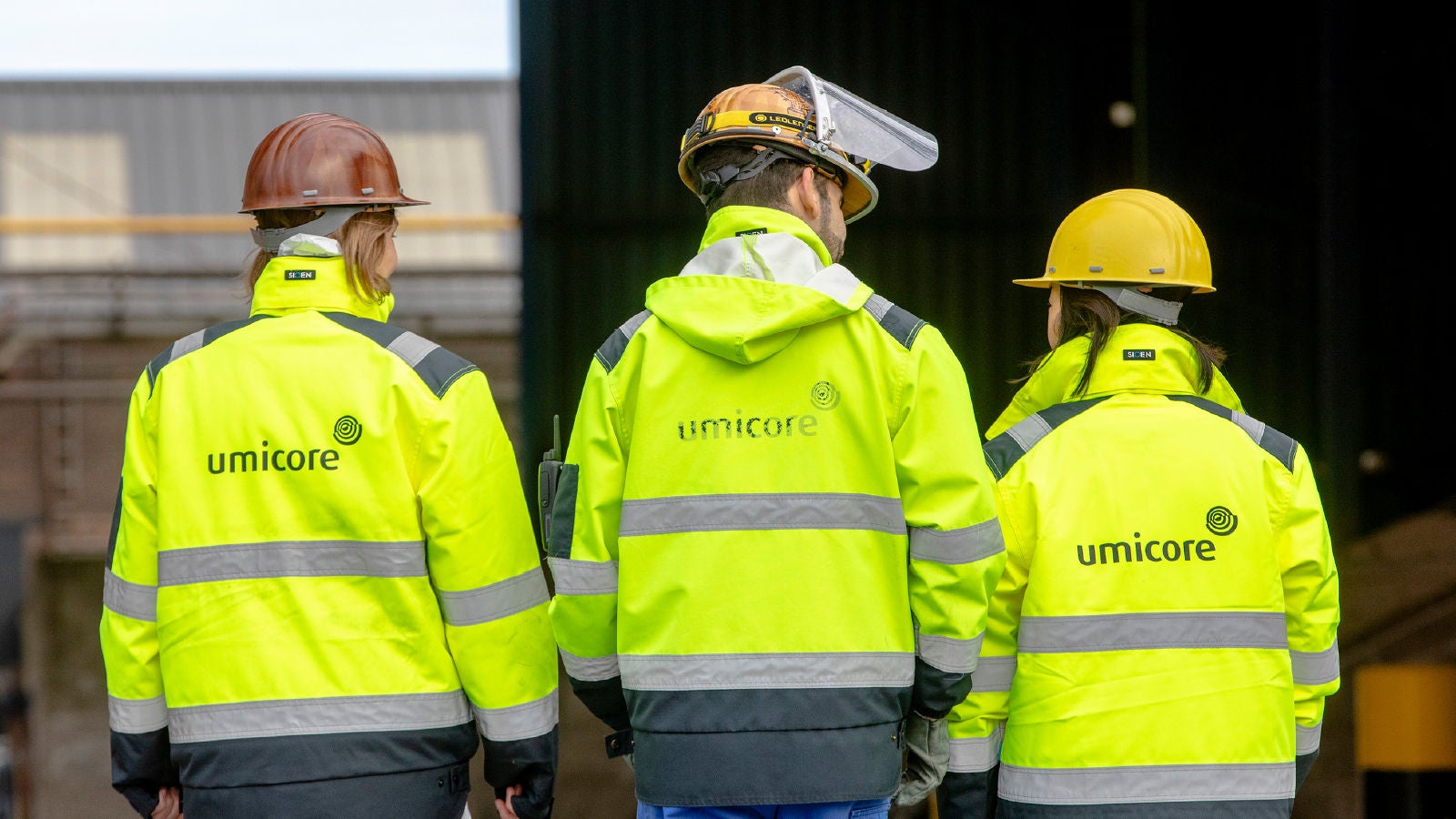 A professional in a data center adjusting server equipment while holding a laptop. The scene is illuminated with green lighting, giving a high-tech ambiance.