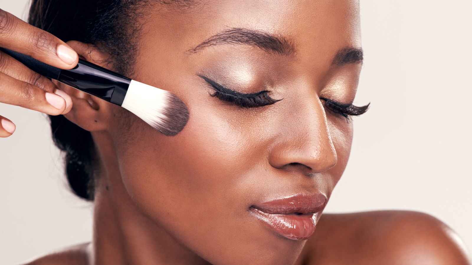 Close up of hands holding a parfume bottle next to a retail shelf full of fragrances