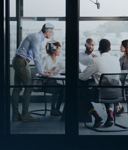 Group of colleagues gathered around a conference table, collaborating and discussing documents in a modern office.