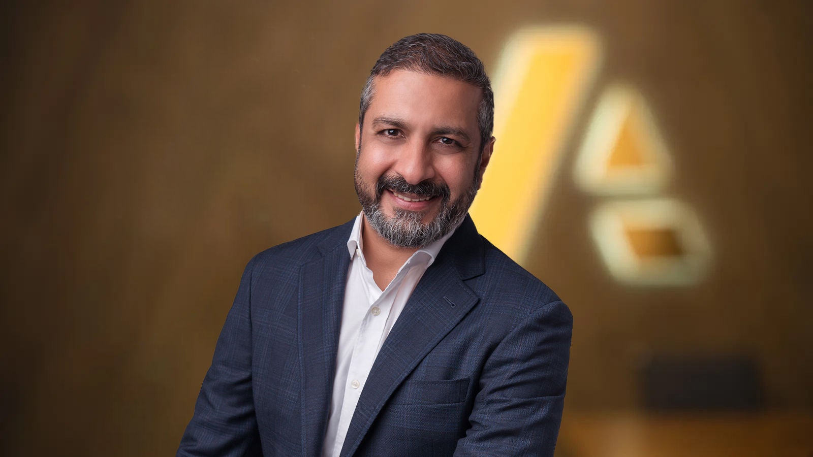Amit Bagga — businessman dressed in suit standing in front of Anaplan logo