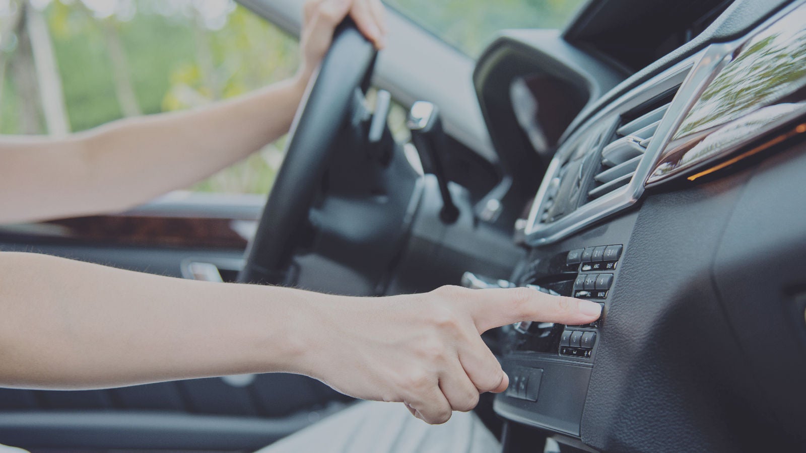 A driver pushing buttons on a dashbaord of a car 