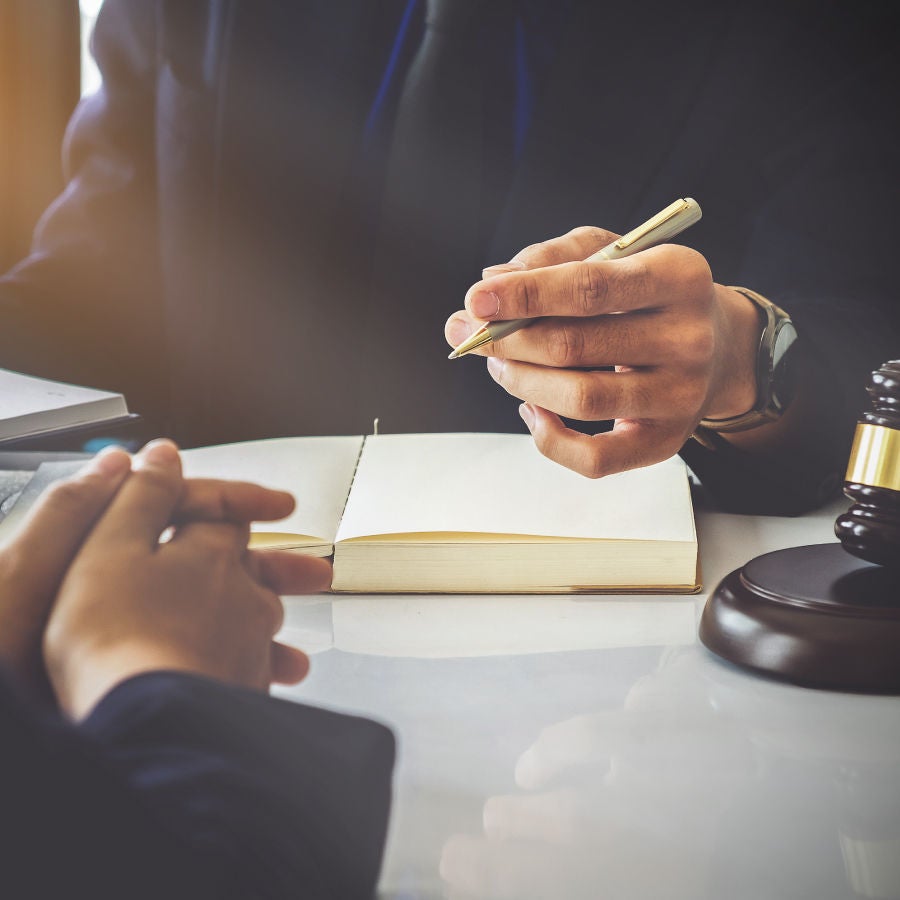 A lawyer and client seated at a desk, discussing legal matters in a formal office environment.