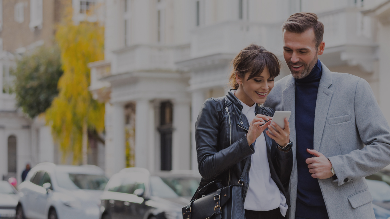 Two people smiling looking at a cell phone
