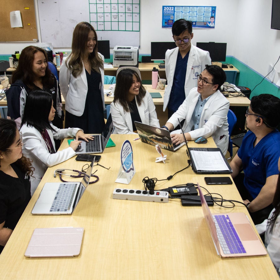 A diverse group of individuals engaged in conversation while seated around a table in a collaborative setting.