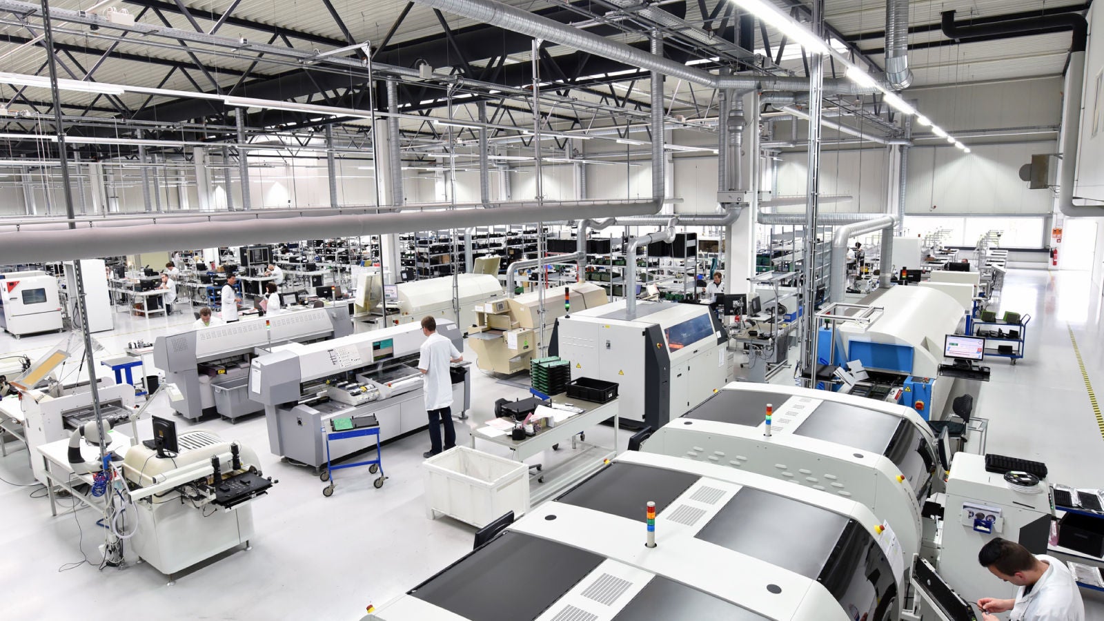 View of a modern electronics manufacturing floor with technicians operating high-tech machinery.