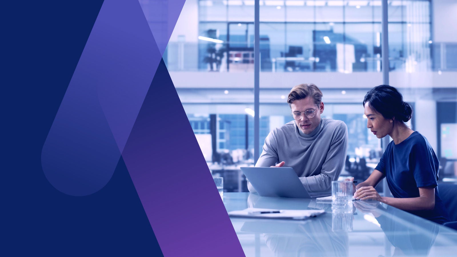 Man and woman siting at office table looking at a laptop together
