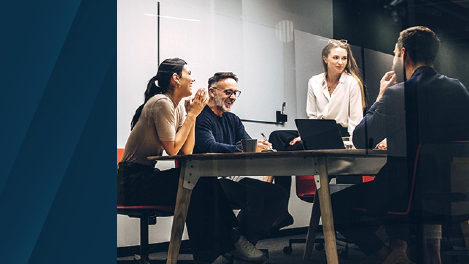 The image shows a team of four people in a modern conference room engaged in discussion, suggesting strategic planning and teamwork.