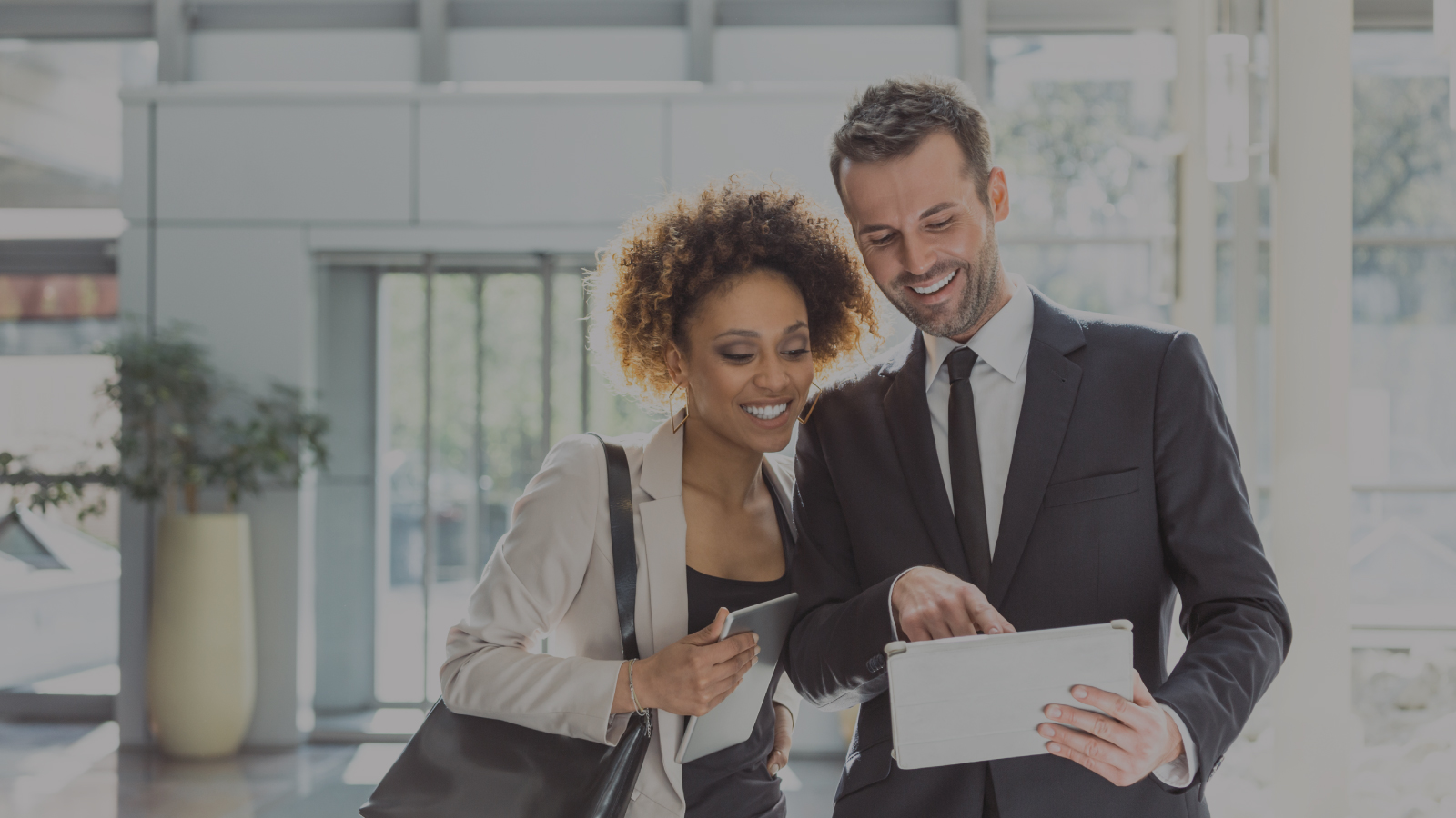 Man and woman smliing and looking at tablet together