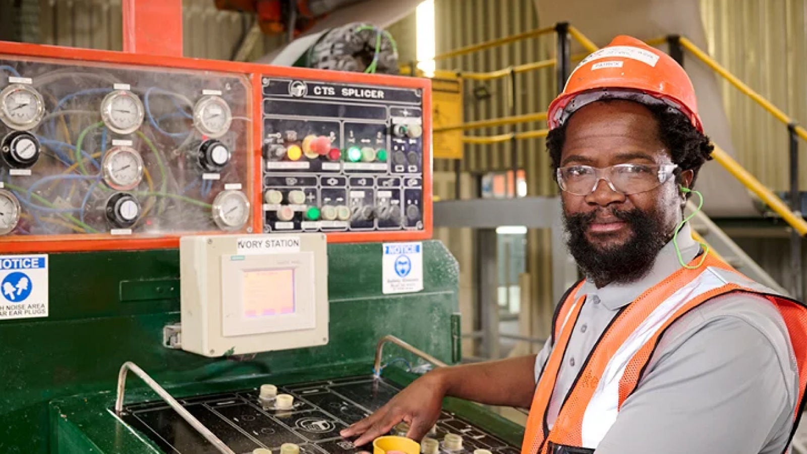 A professional in a data center adjusting server equipment while holding a laptop. The scene is illuminated with green lighting, giving a high-tech ambiance.