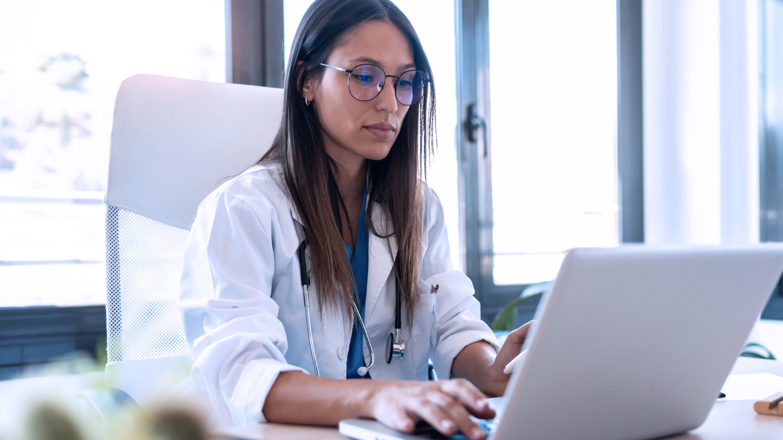 Anonymous Healthcare Organization Customer Story Office Image 2 Doctor typing on a laptop at her desk