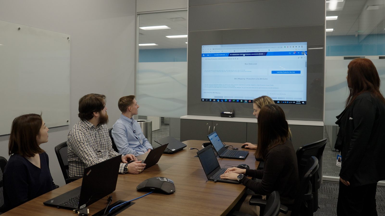 Daikin employees in a conference room looking at an Anaplan Dashboard projected on the wall