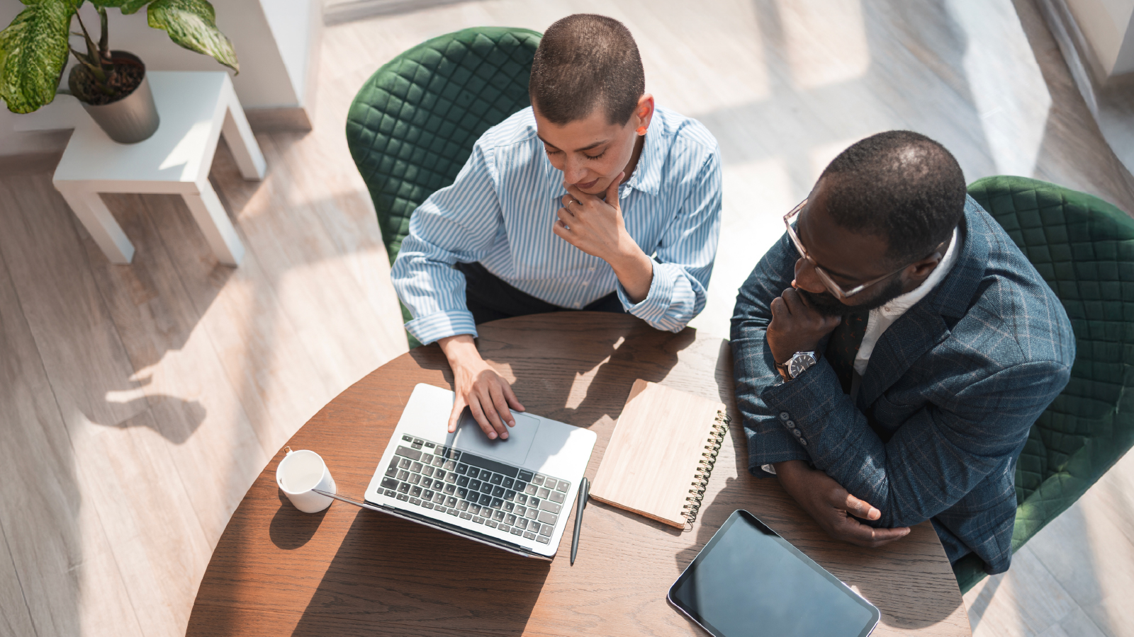 Two coworkers collaborating at a table on a laptop