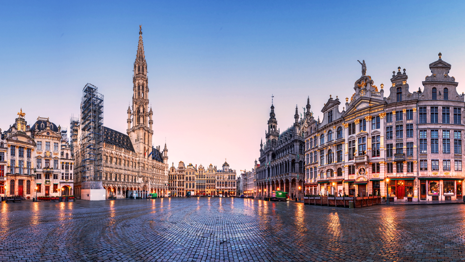 Anaplan event image for Connect 2025 Brussels. A panoramic view of the Grand Place at twilight, showcasing ornate historic buildings with golden accents and a wet cobblestone plaza reflecting the soft evening light.