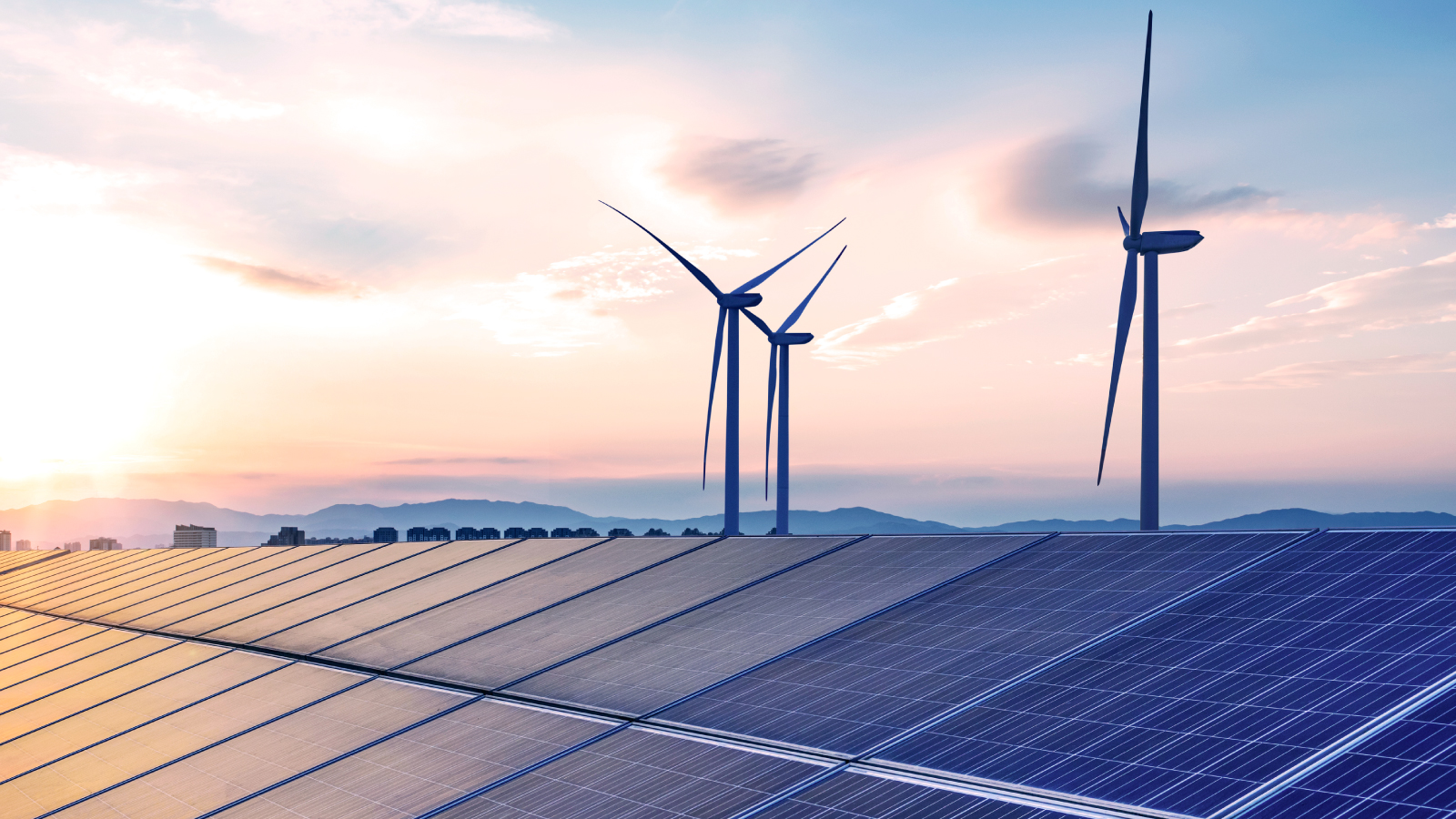 Solar panels and wind turbines under a colorful sunset sky, representing clean energy and sustainability.
