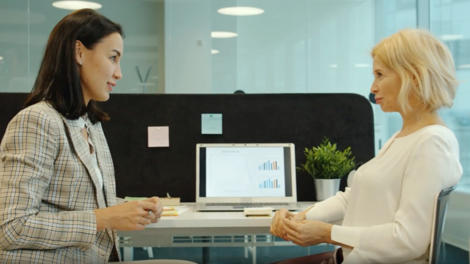 Female colleagues chatting at ones desk