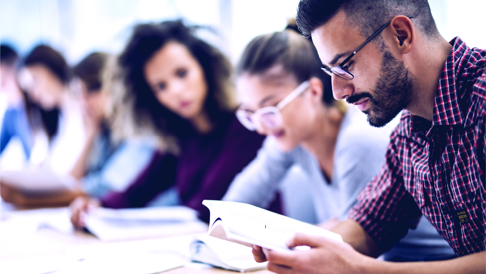 Students studying in class. Foreground, student in dress shirt wearing glasses