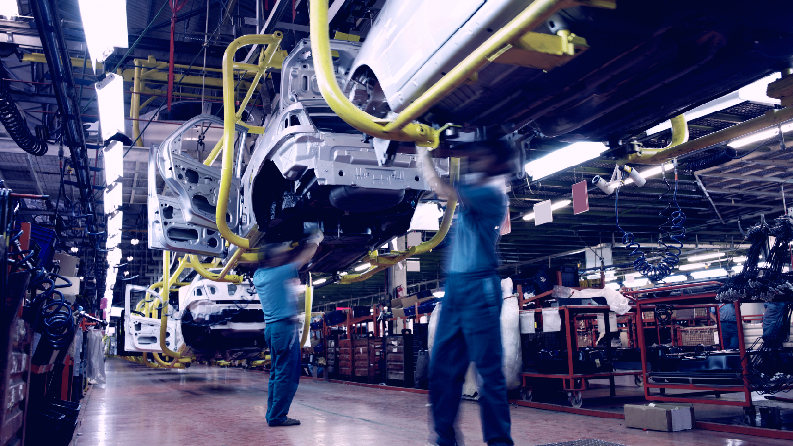 Two factory workers inspecting vehicles on factory line