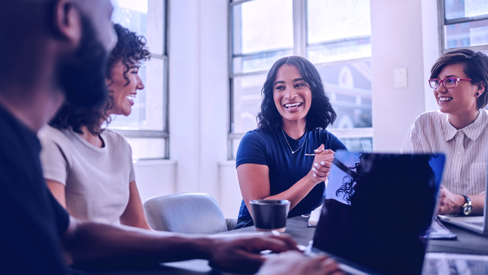 Group of coworkers at a desk laughing while working