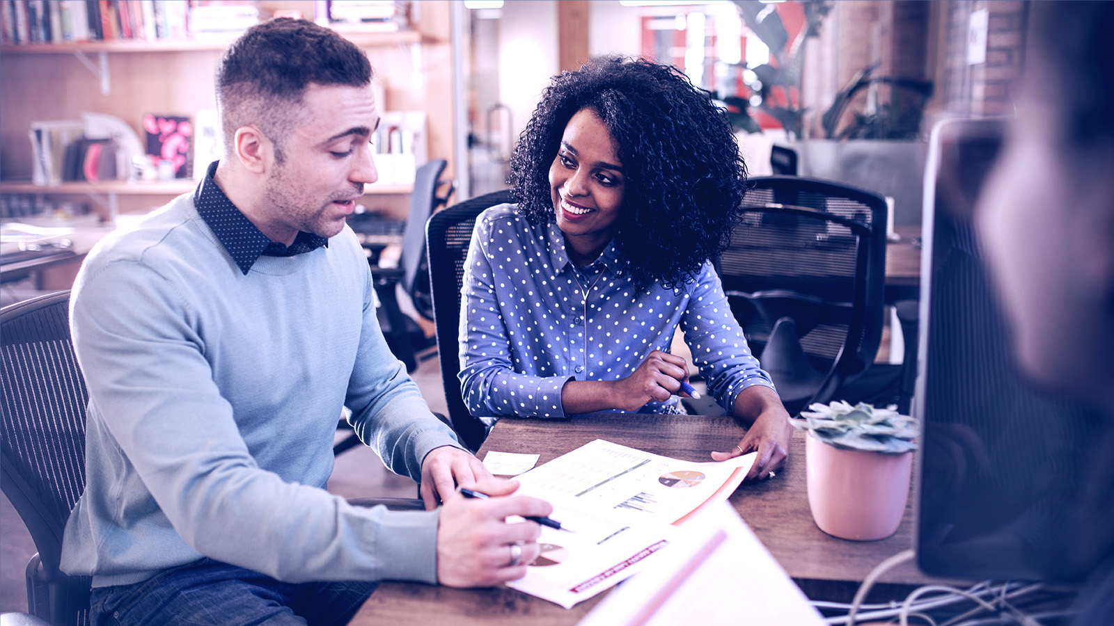 Coworkers seated at a table, papers and graphs in front of them