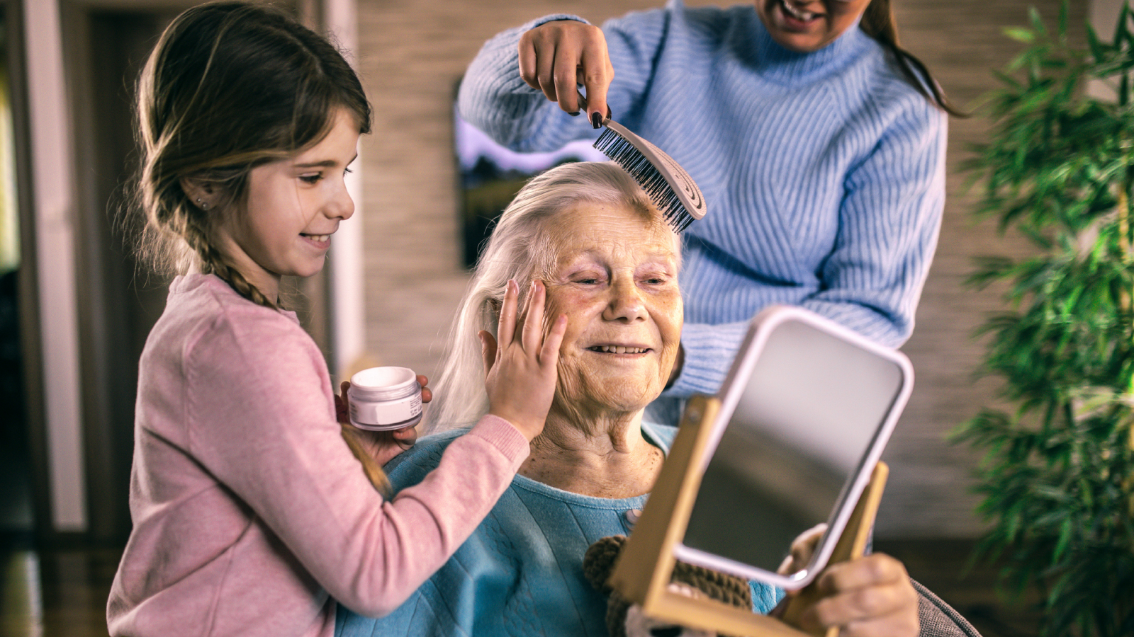 Older woman looking in mirror while granddaughter applies lotion to her face