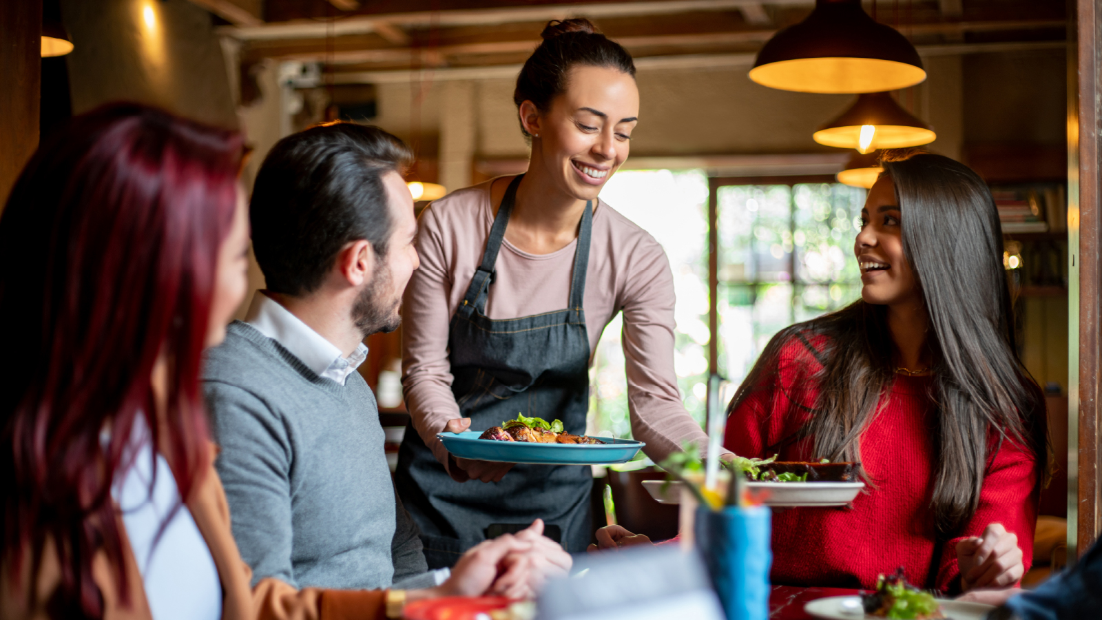 Woman serving a table of patrons at a restaurant