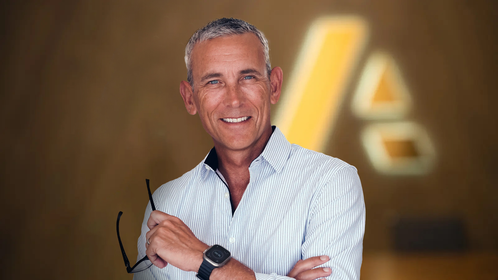 Dayne Turbitt — businessman dressed in suit standing in front of Anaplan logo