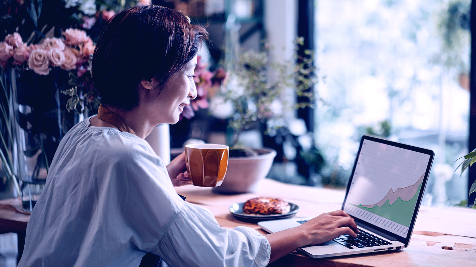 Une femme sourit en regardant un graphique sur un ordinateur portable.