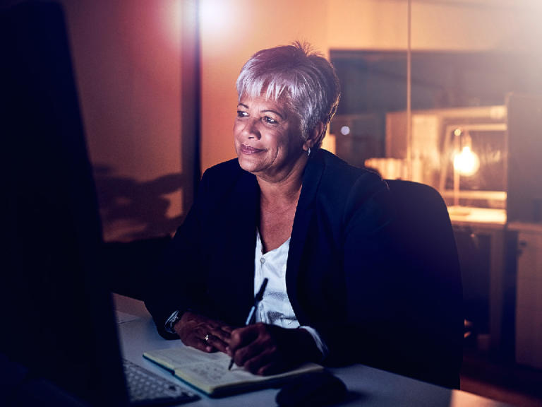 Older woman taking notes from a computer presentation