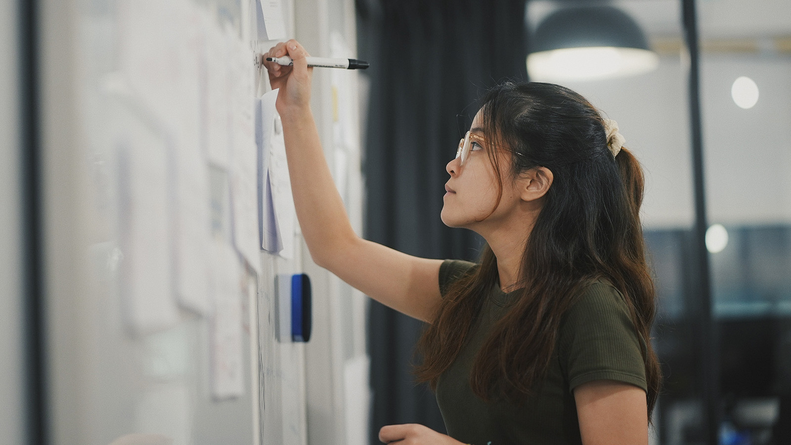 Asian woman writing on whiteboard